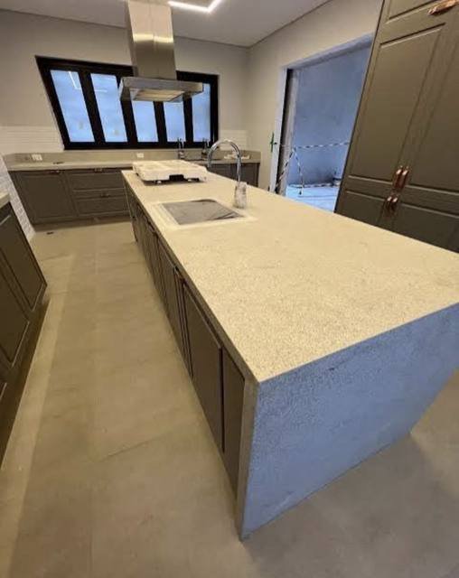 Ilha de cozinha em quartzo branco, com cuba e cooktop integrados.