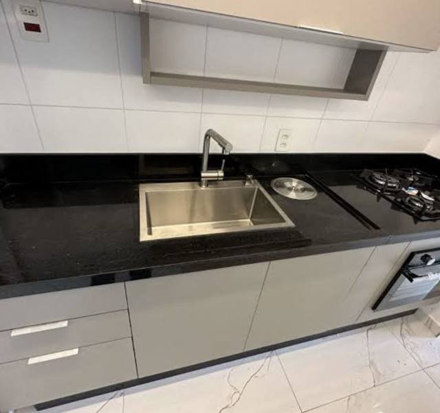 Bancada em granito preto com cuba e cooktop integrados.